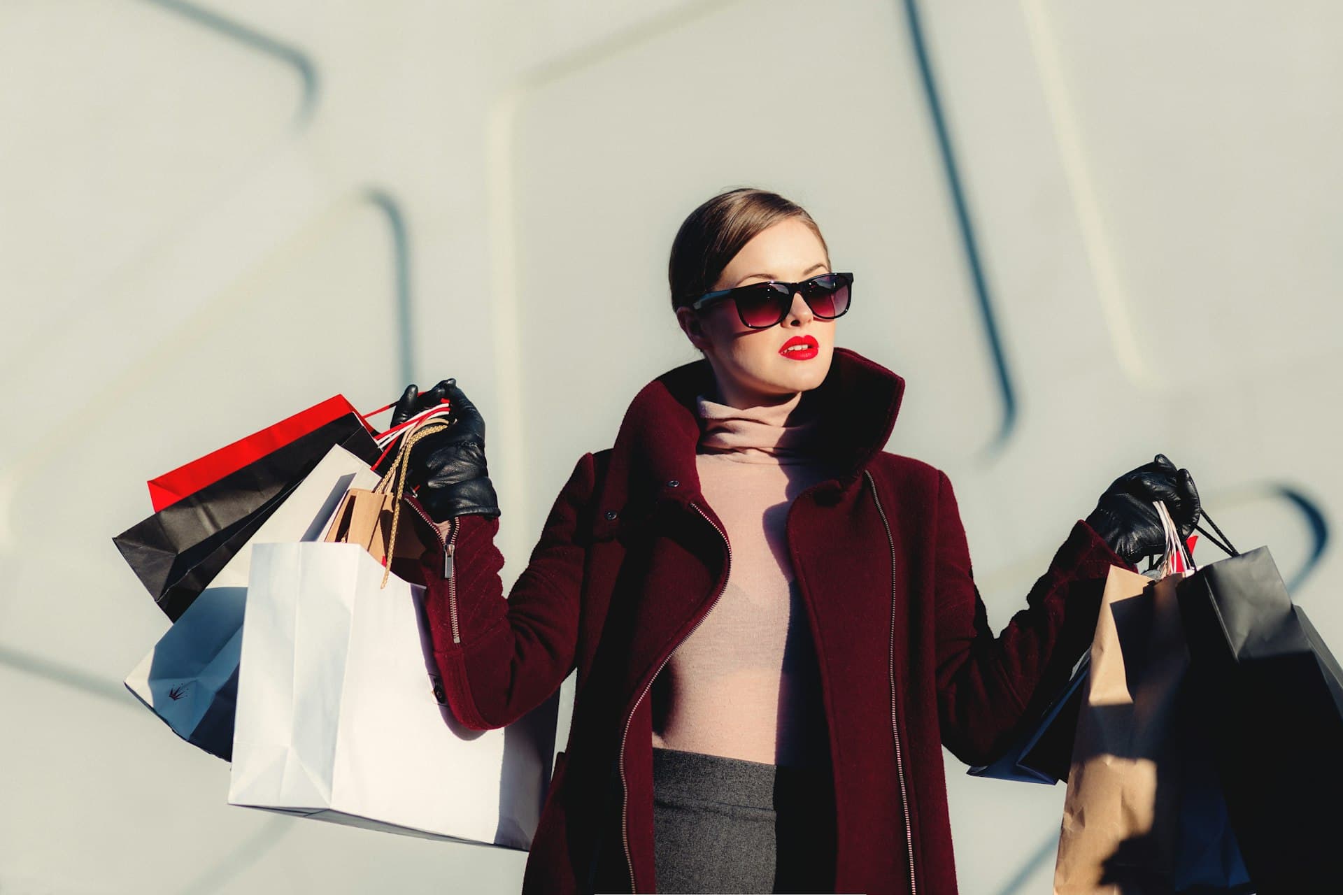 Woman in a burgundy coat holding shopping bags