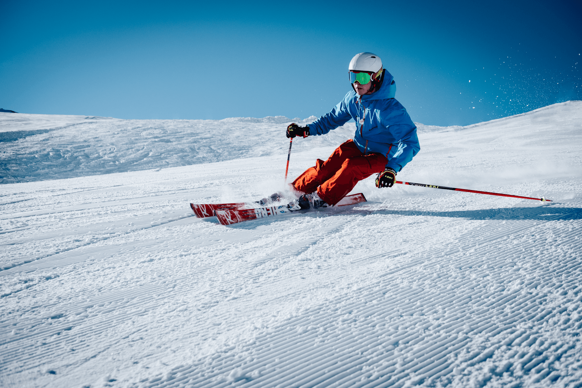 Skier carving down a groomed alpine slope